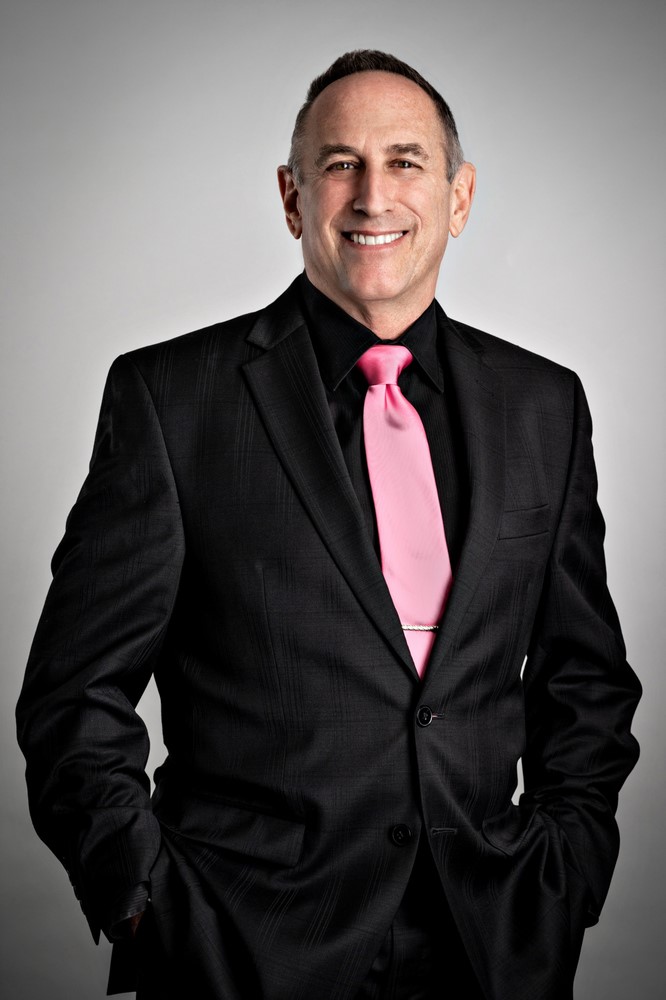 Larry Paul - The Mortgage Answer Guy smiling in a dark suit with pink tie